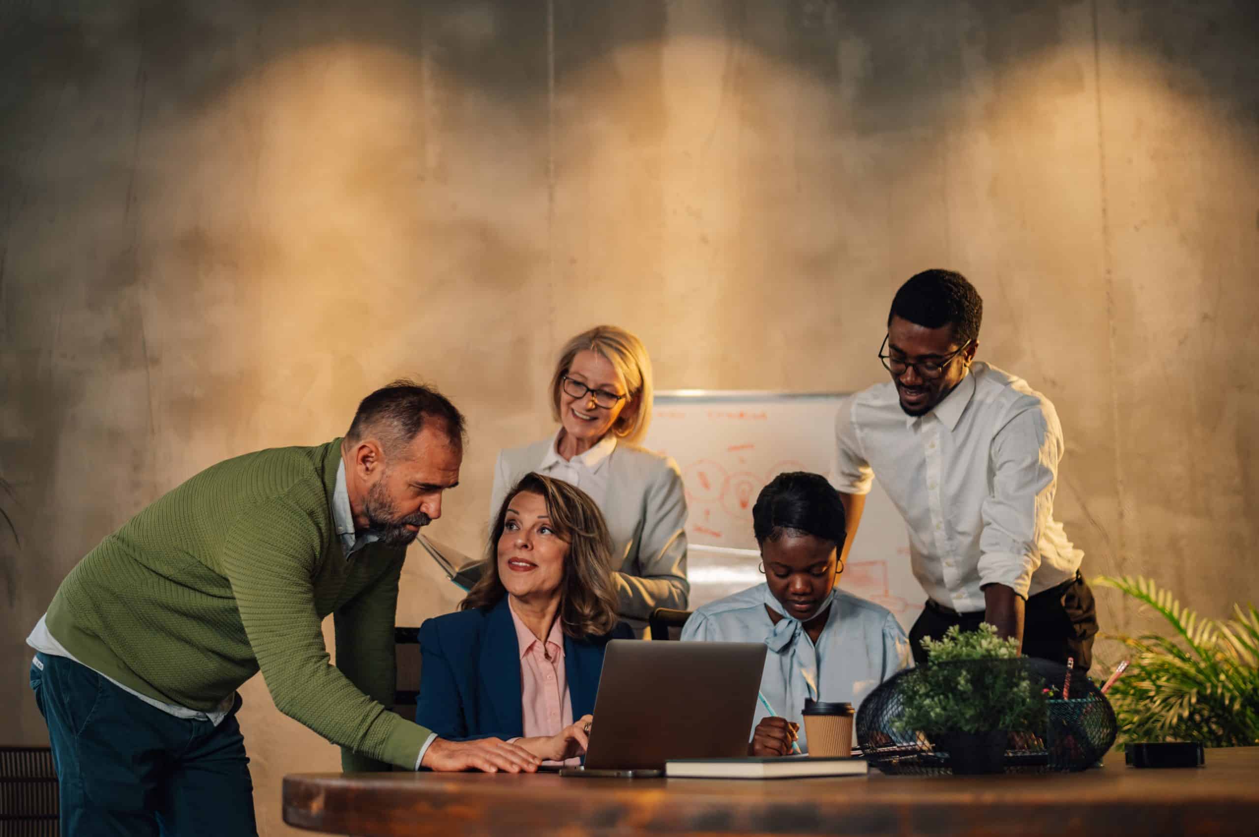 Happy multiracial business team working together at corporate briefing gathered at table in the conference room. Smiling diverse colleagues in a boardroom discussing business together
