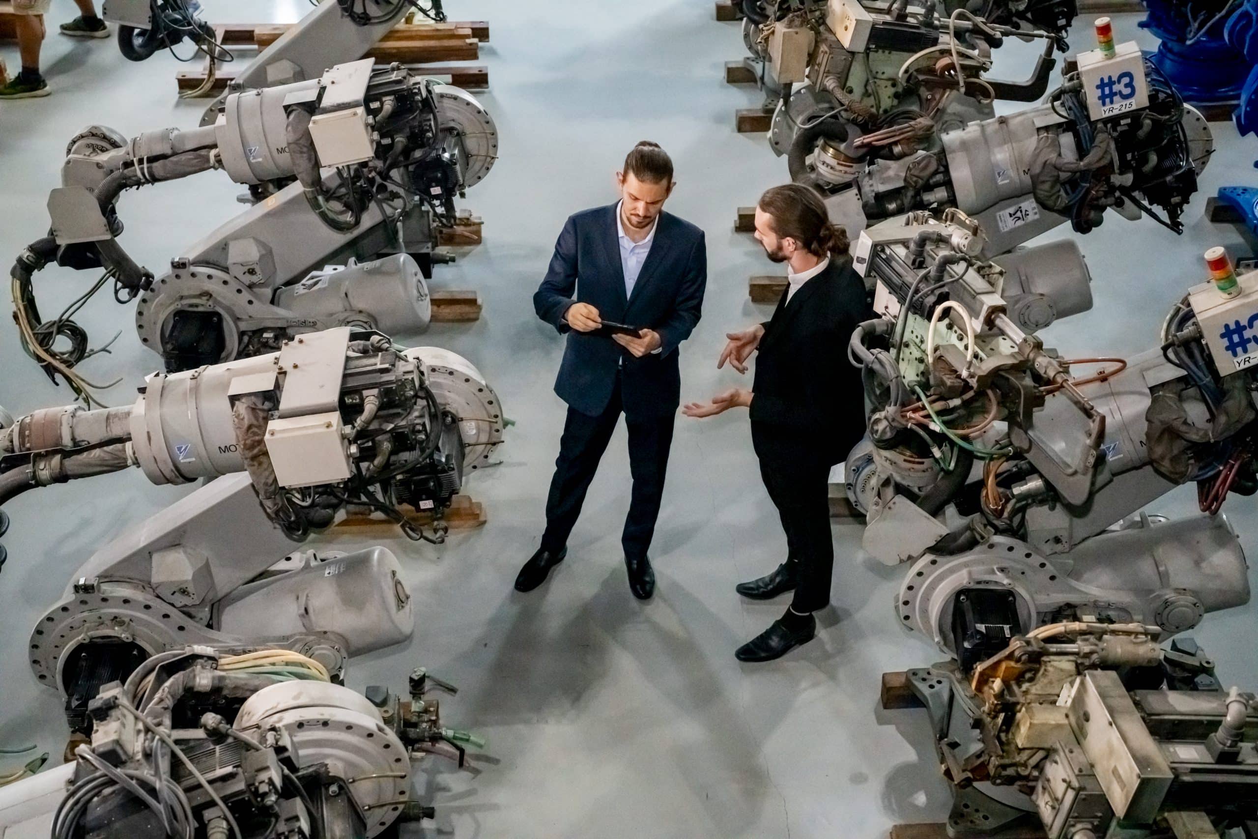 Businessman pointing toward machinery while walking by coworker at industry